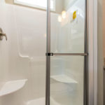 Image of standard white 1-piece fiberglass 48 inch walk in shower. Image shows standard transom window over shower.