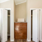 Image of optional dual closet setup. White bi-fold doors are standard closet doors. Image also shows standard shelf and rod for closets.