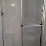 Image of standard 1-piece white fiberglass 48" walk-in shower with door and standard elongated commode.