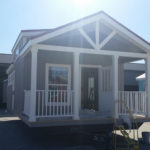 Image shows standard 6' covered front deck. Customer has choice of painted wooden rails or white vinyl rails standard.