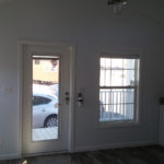 Image shows upgraded front door to 36X80 white steel door with built in blinds. Upgrade to have ceiling fan installed in over living room also shown in this image.